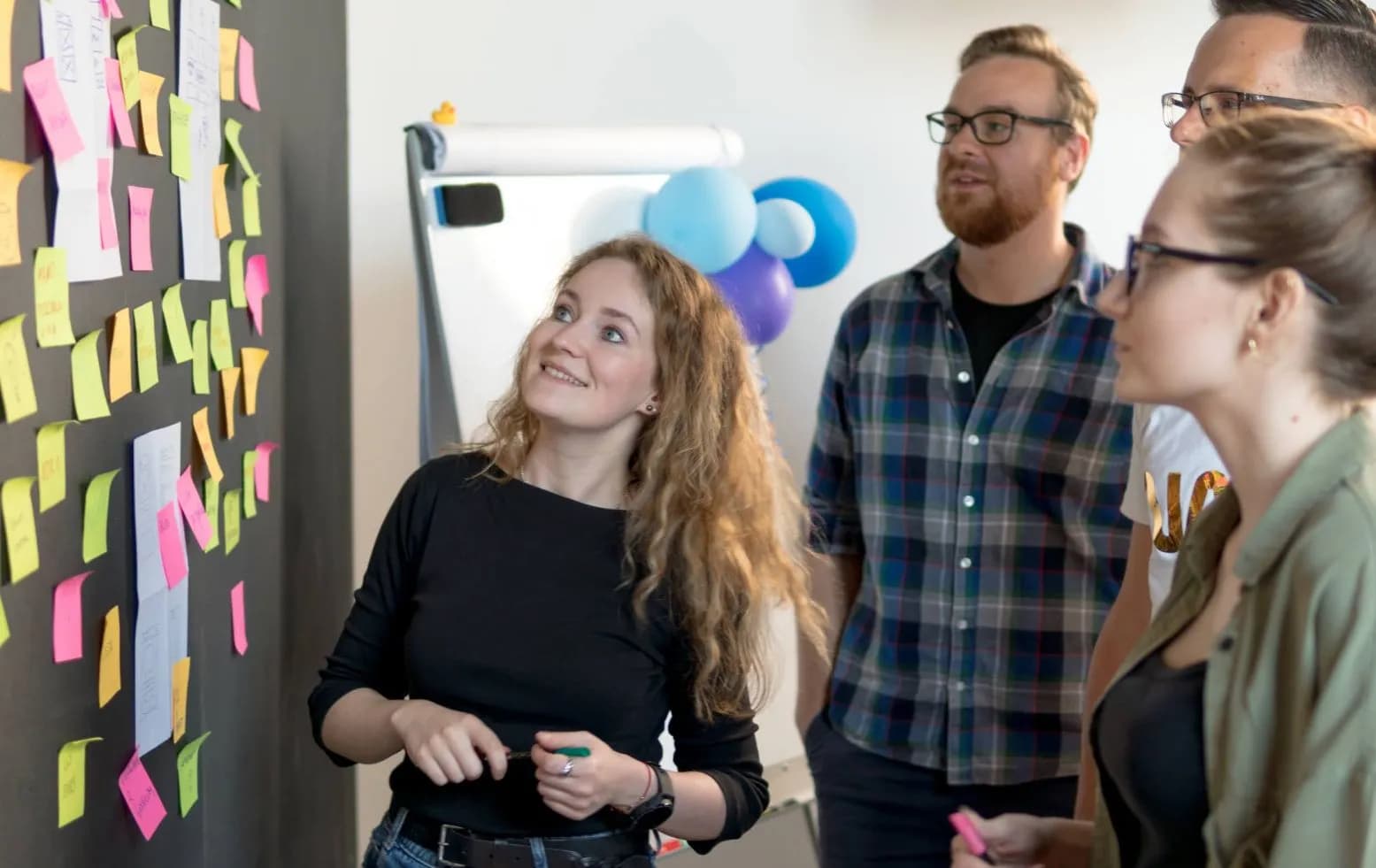 Results of a software development workshop at Revolve Healthcare Four people looking at a black wall full of colourful sticky notes after a software development workshop